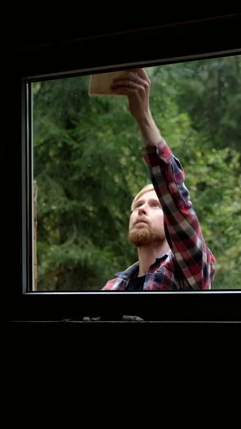 Man working on window frame, camera pans up to reveal progress in scene Stock Footage 322117395