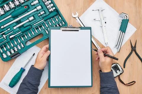 Man working in workshop holding clipboard using many tools. Wrench, spanner.. Stock Photos