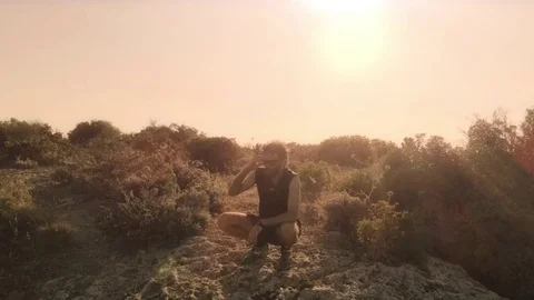 Man in workout clothes sits on top of a cliff on an island admiring the 動画素材 78023461