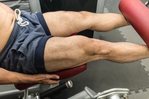 Man workout with Leg Extensions for builder muscle in upper leg exercise in g Stock Photos