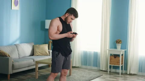 Man Is Workouting at Home Using Smartphone Stock Footage 138510789