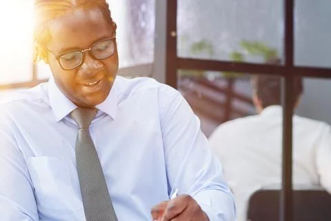 A man at a workplace at a table in front of a computer writes down notes Stock Photos