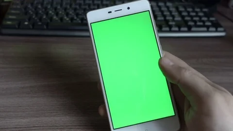 Man in the workplace using his smartphone with green screen, scrolling news,  Stock Footage 82834044