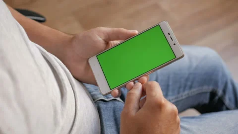 Man in the workplace using his smartphone with green screen, scrolling news,  Stock Footage 101283632