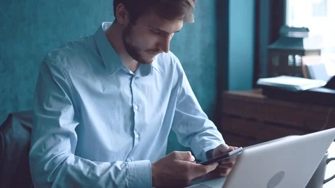 Man in the workplace using his smartphone, scrolling news Stock Footage 123916371