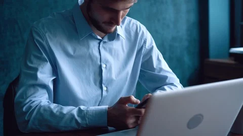 Man in the workplace using his smartphone, scrolling news Stock Footage 123916380
