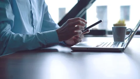 Man in the workplace using his smartphone, scrolling news Stock Footage 123916384