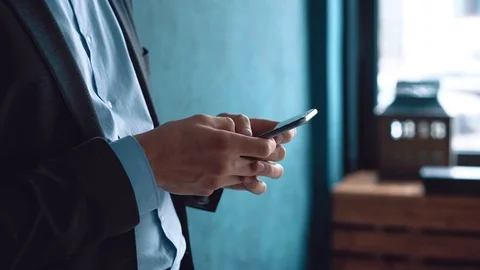 Man in the workplace using his smartphone, scrolling news Stock Footage 123916390