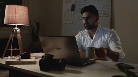 Man Works Back Late in Dark Office at Night, Drinks Coffee at Desk - Wide Shot Stock Footage 108892181
