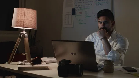 Man Works Back Late in Dark Office at Night, Takes Notes at Desk - Wide Shot Stockbeeldmateriaal 108892246