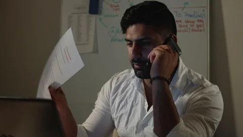 Man Works Back Late in Dark Office at Night, Talks on Phone with Boss or Client Stock Footage 108893384