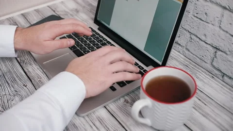 A man works at the computer and drinks tea Stock Footage 142606378