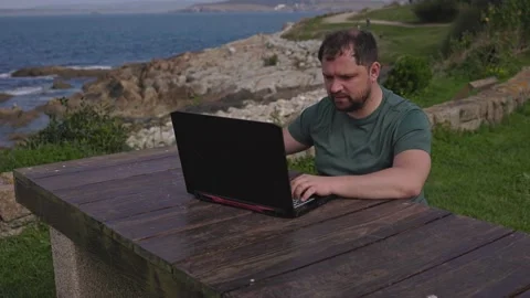 A man works at a computer in the fresh air. Stock Footage 179621741