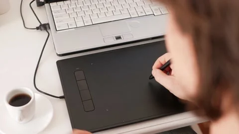 Man works at computer on graphics tablet and drinks coffee. Freelancer, work at Video stock 165046106