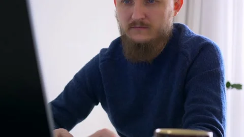 A man works at a computer at home. Remote work, a man sits at a table on which Stock Footage 171103980