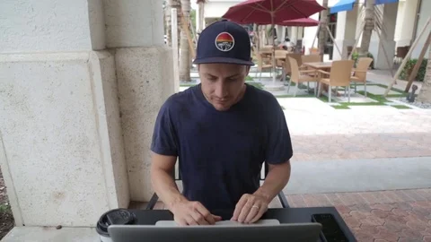 Man Works on Computer Outside a Coffee Shop Stock Footage 76483968