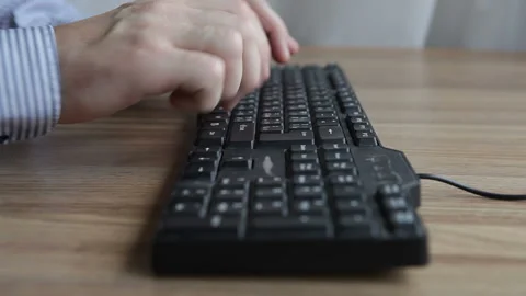 A man works at a computer, typing text on the keyboard. Office worker Video stock 165165123