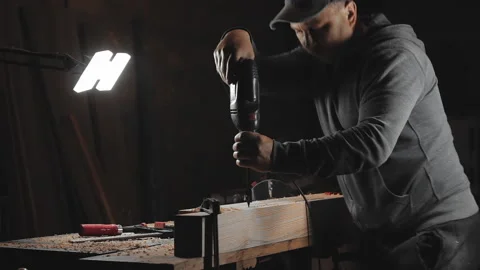 A man works with a drill in his workshop Stock Footage 194681307