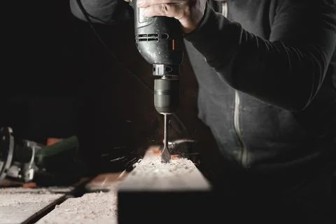 A man works with a drill in his workshop. Carpenter drills with a hand power  Stock Photos
