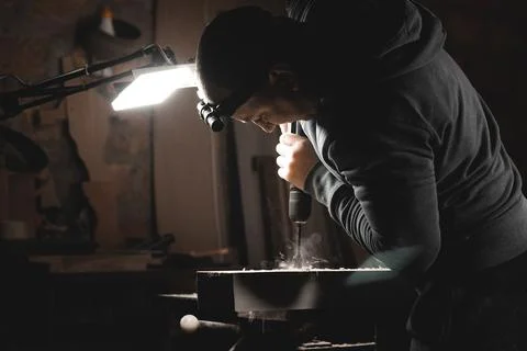 A man works with a drill in his workshop. Carpenter drills with a hand power  Stock Photos