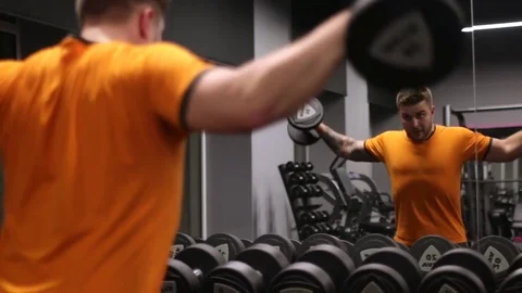 The man works with dumbbells on the muscles of the shoulders Stock Footage 83129341
