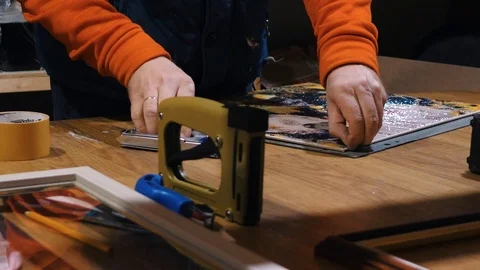 A man works in a framing studio. A man stretching canvas 库存影片 101953573