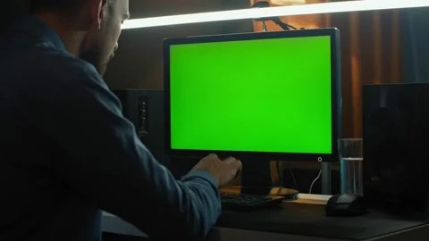 A man works in front of a computer with a green screen. Video stock 169446686