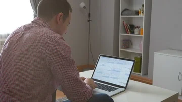 Man in works from home using the top and trackpad. Young business man sitting at Stock Footage 86043352