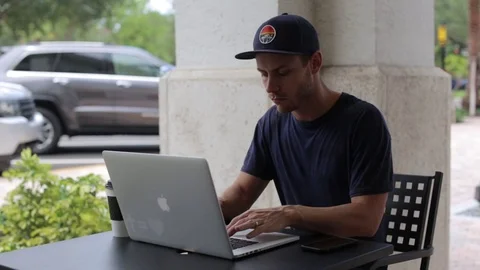 Man Works on Laptop Computer Outside Coffee Shop Stock Footage