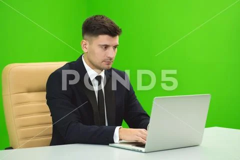 The man works with the laptop on the green background Stock Photos