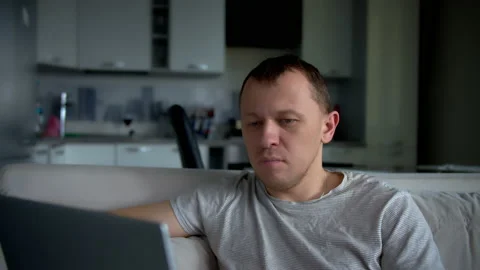 A man works on a laptop while sitting at home on a sofa, remote work Stock Footage 132449776