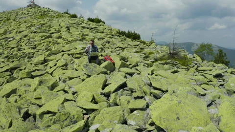 A man works on a laptop while sitting on top of a rocky mountain. Stock Footage 248203477