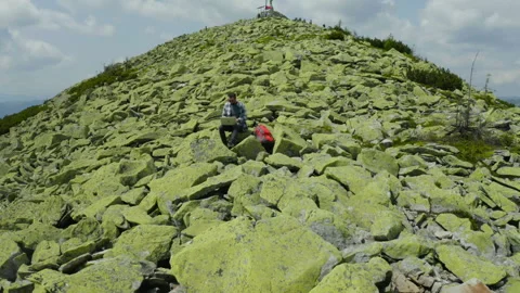 A man works on a laptop while sitting on top of a rocky mountain. Видео 248203578