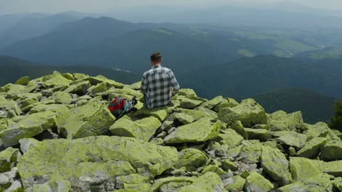A man works on a laptop while sitting on top of a rocky mountain. Stock Footage 248204059