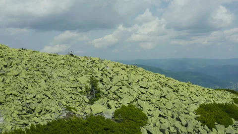 A man works on a laptop while sitting on top of a rocky mountain. Stock Footage 248204216