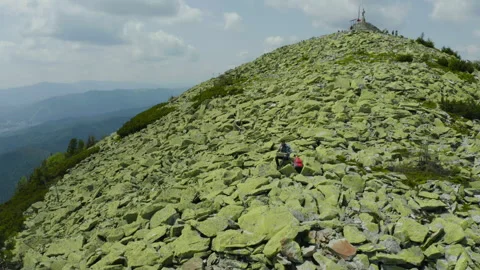 A man works on a laptop while sitting on top of a rocky mountain. Stock Footage 248204353