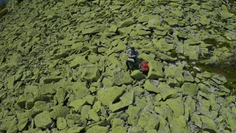 A man works on a laptop while sitting on top of a rocky mountain. Stock Footage 248205707