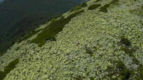 A man works on a laptop while sitting on top of a rocky mountain. Stock Footage 248205905