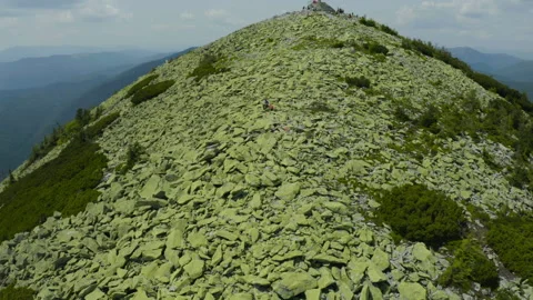 A man works on a laptop while sitting on top of a rocky mountain. Stock Footage 248206209