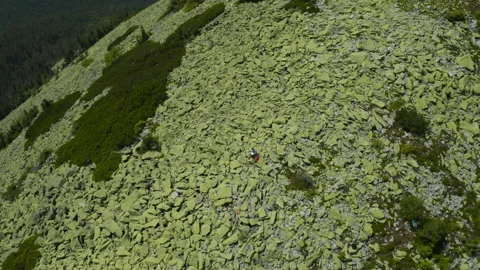 A man works on a laptop while sitting on top of a rocky mountain. Stock Footage 248206284