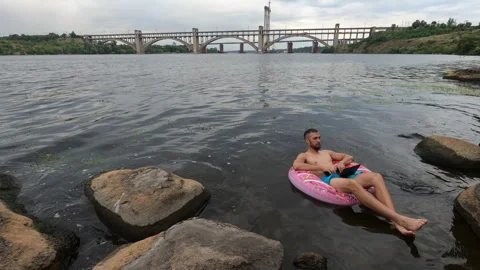 A man works on a laptop while swimming in inflatable ring Stock Footage 274222701
