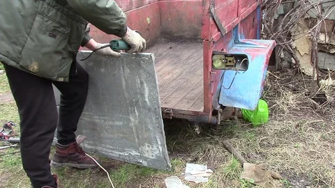 Man works metal angle grinder. Worker Restores old car trailer with metal Stock Footage 124592971