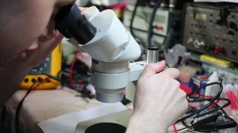 Man works with microscope among tools for repair of electronics Video stock 51874430