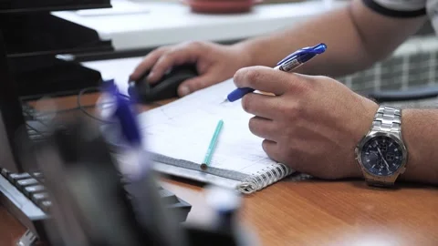 A man works in the office at the computer and makes notes in a notebook Stock-Footage 154900348
