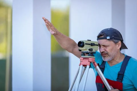 A man works with an optical level to level the landscape. Stock Photos