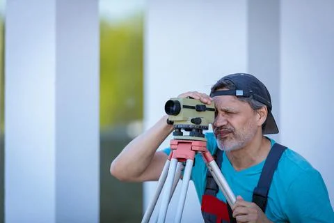 A man works with an optical level to level the landscape. Stock Photos