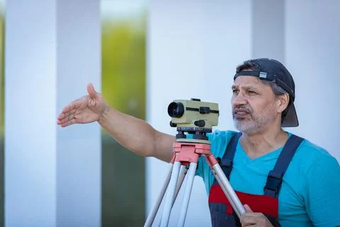 A man works with an optical level to level the landscape. Stock Photos