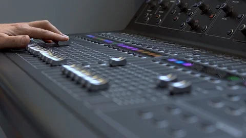 Man works on a professional electronic audio mixer. A control panel for tuning Stock Footage 114084431