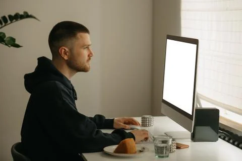 A man works remotely using a desktop computer holding a tablet computer at ho 스톡 사진