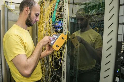 The man works in the server room of the datacenter. A technician measures the Stock Photos